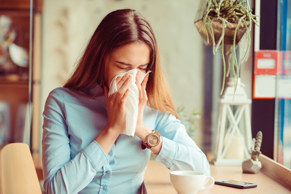 woman sneezing in a dusty office